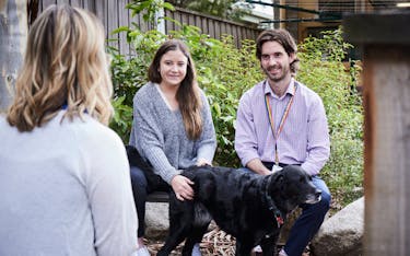 Wellways staff Three Wellways staff members sitting outside chatting and patting a dog