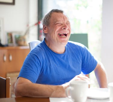 Man in a blue tshirt sitting at a dining table with a cup of coffee Man in a blue tshirt sitting at a dining table with a cup of coffee